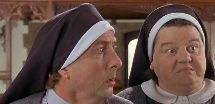 Screengrab from the 1990 British comedy Nuns on the Run with close-up shot of actors Eric Idle and Robbie Coltrane looking shocked.